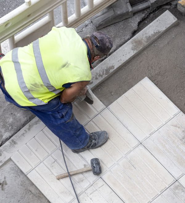 Construction worker with angle grinder repairing a sidewalk. Maintenance concept